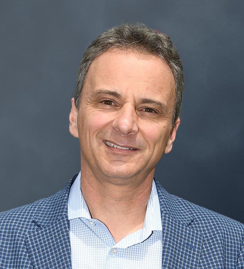 A man in a blue suit smiling for the camera.