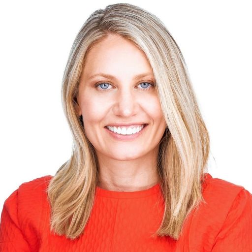 Woman with blonde hair wearing a red top smiling against a white background.