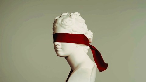 A statue of a woman with a red blindfold on her head, symbolizing the human experience in the realm of science.