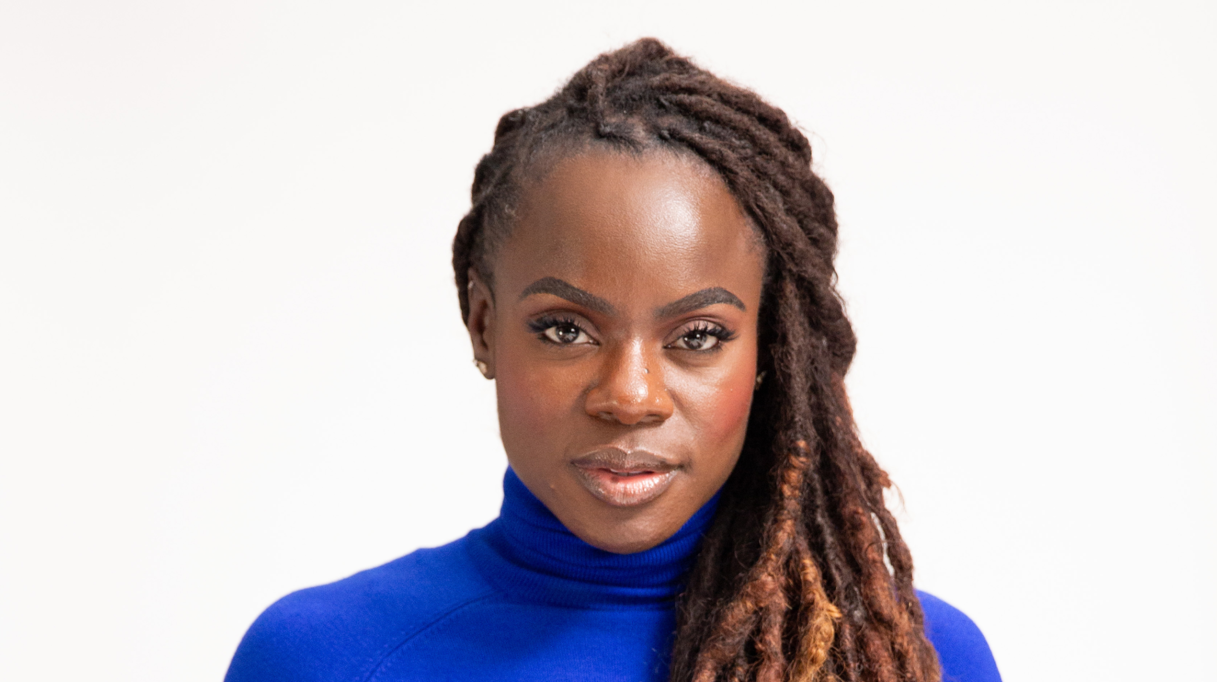A woman with dreadlocks wearing a blue turtle neck.