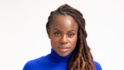 A woman with dreadlocks wearing a blue turtle neck.