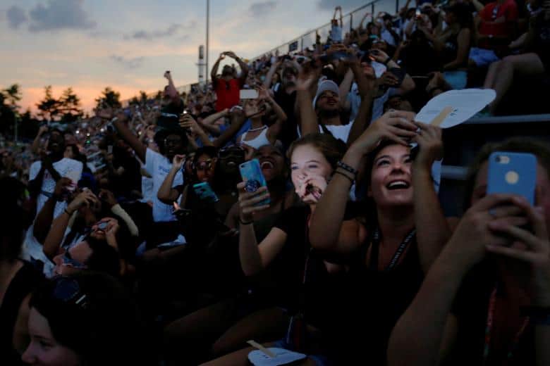 Crowd of people enjoying a total eclipse, capturing moments on their mobile phones.