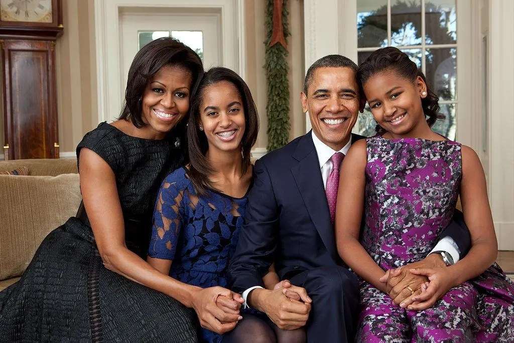 A family of four smiling and posing together for a portrait in a formal room, capturing the complex beauty of life.