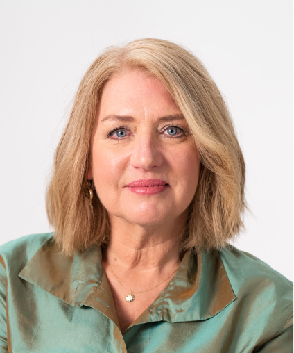 Portrait of a middle-aged woman with blonde hair, wearing a green blouse, smiling slightly at the camera on a white background.