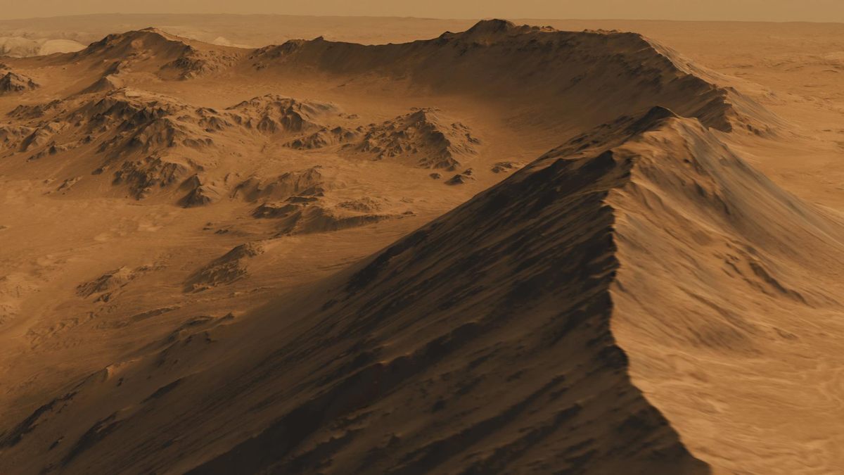 Rugged martian terrain featuring sharp, towering peaks and deep valleys under a hazy orange sky.