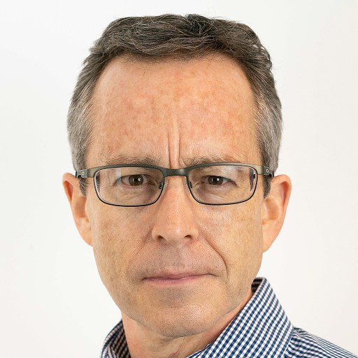 A middle-aged man with short brown hair, wearing glasses and a checkered shirt, looking directly at the camera with a neutral expression.