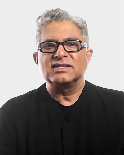 A person with short gray hair, wearing glasses and a black shirt, looking directly at the camera with a neutral expression.