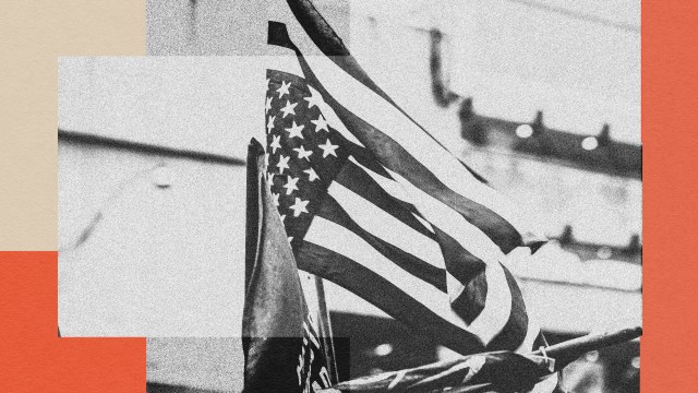 Black and white photo of an American flag waving against a blurred background of buildings, framed by red and beige rectangular blocks.