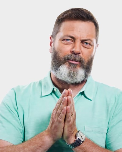 A man with a beard and mustache, wearing a light green shirt, holds his hands together in front of him. He has light skin and dark hair.