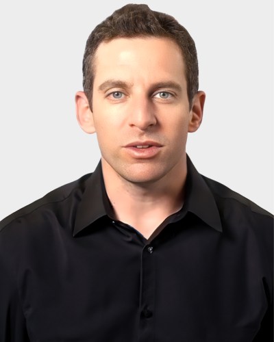 Portrait of a man with short dark hair wearing a black collared shirt, facing forward against a plain white background.