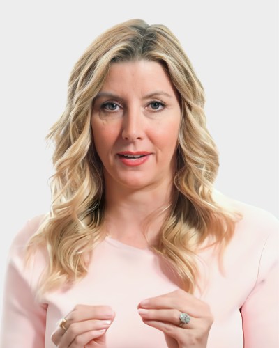 A woman with long blonde hair and a light pink top is speaking and gesturing with her hands. The background is plain white.