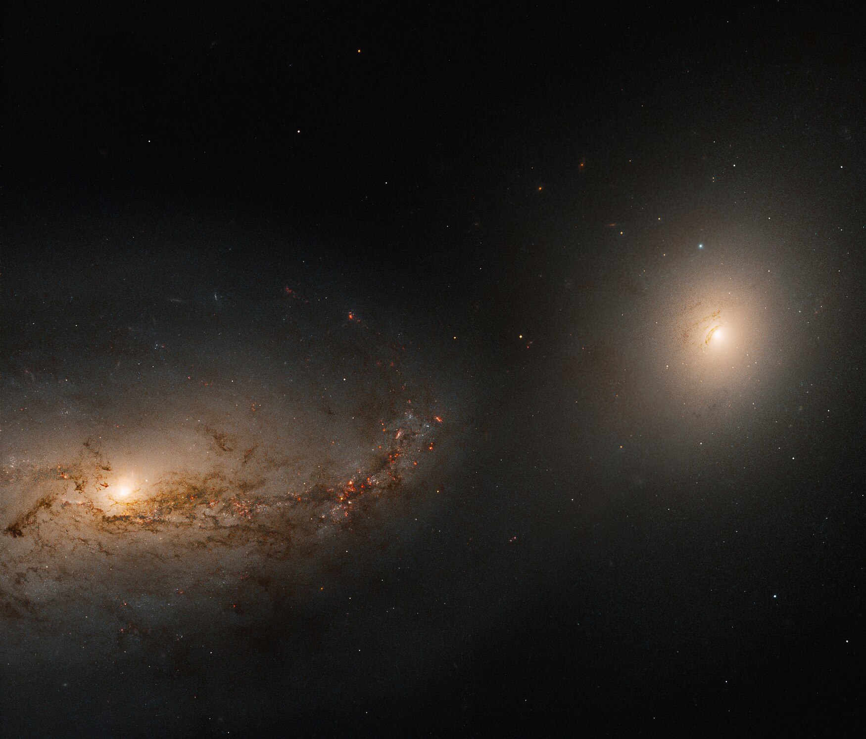 A detailed image of two galaxies in space, one with spiral arms on the left and the other, more elliptical, on the right, surrounded by distant stars.