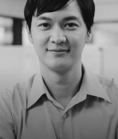 Black and white portrait of a person with short hair, smiling slightly, and wearing a light-colored shirt.