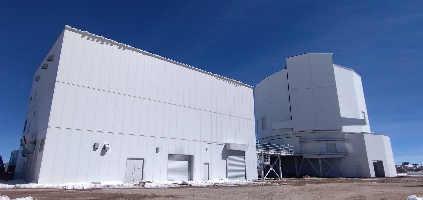 Large white industrial buildings under a clear blue sky, ideally situated at one of the best locations on Earth for astronomy.