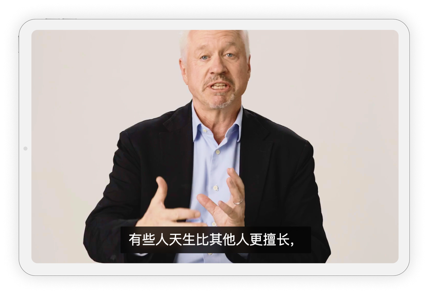 A person speaking in a video, wearing a suit jacket and shirt. Chinese subtitles are displayed at the bottom.