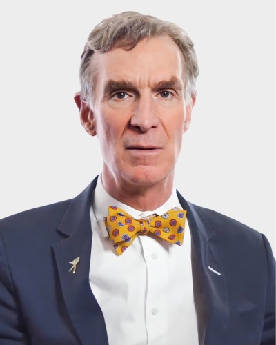 Person wearing a suit with a yellow bow tie featuring circular designs, against a plain background.