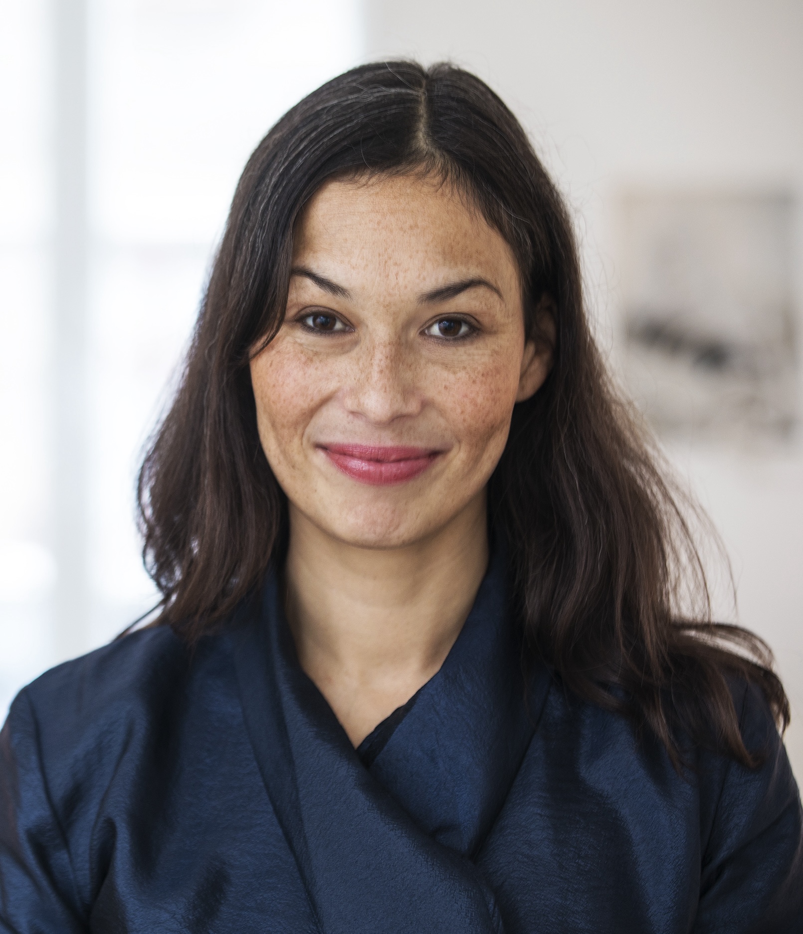 Woman with long dark hair and a blue blouse smiling at the camera.