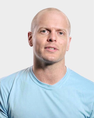 A bald man in a light blue shirt against a plain background.