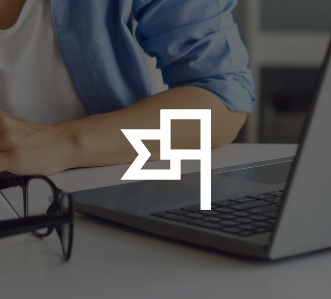 A person in a blue shirt sits at a desk with a laptop and glasses. A white geometric symbol overlays the image.