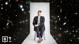 A person in a suit sits on a chair against a cosmic background with galaxies and stars.