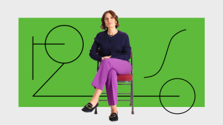 A woman sits on a chair with legs crossed, wearing a navy sweater and purple pants, in front of a green background with black abstract line art.