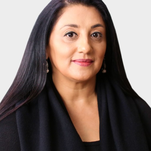 A woman with long, straight dark hair and light skin wears a black top and earrings, posing against a plain light background.