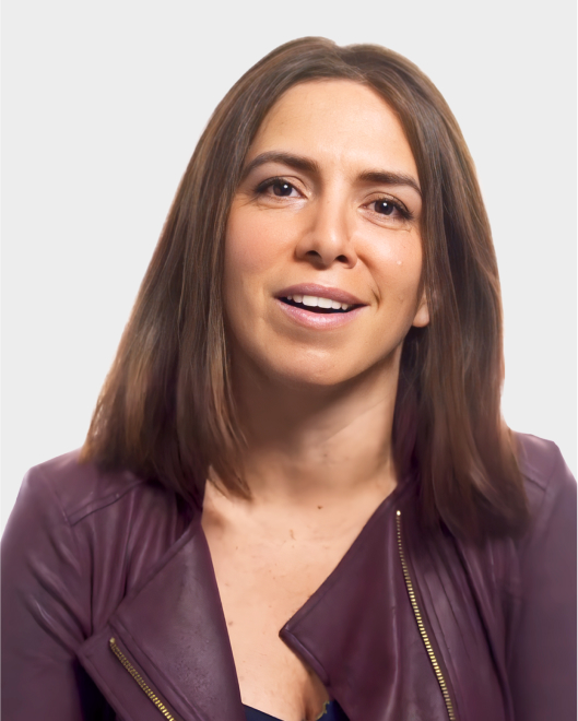 A woman with straight brown hair wearing a burgundy jacket is looking slightly up and smiling against a plain light background.