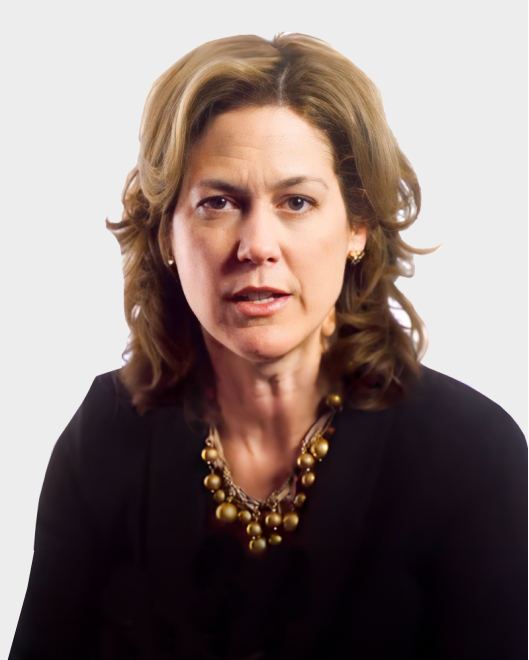 A woman with wavy brown hair wearing a black top and a gold bead necklace, looking directly at the camera with a neutral expression.